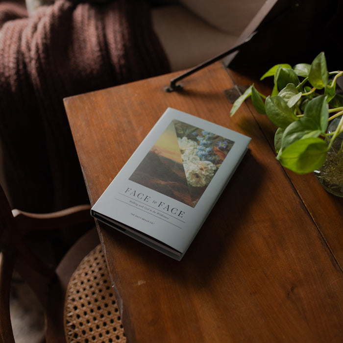 Face to Face Hardcover on a wooden table near a wicker chair