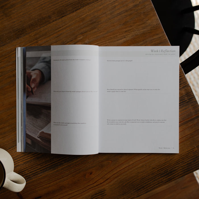 Faith Foundations Mens study opened to week 1 reflection page on a brown wooden table next to a white coffee cup