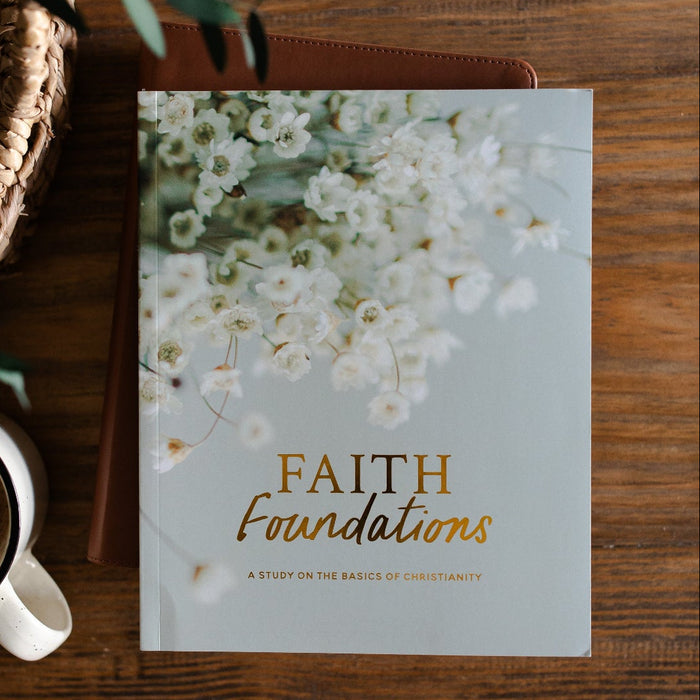 Faith Foundations Matte Study laying on a leather book next to a cup of coffee in a white mug; The study and the coffee is on a brown wooden table next to a hand woven basket