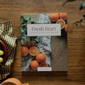 Fresh Start Bible study cover on a wooden table next to a bowl of grapes and a coffee cup