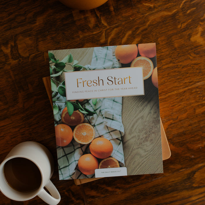 Fresh Start Bible study on a brown journal and a wooden table next to a white coffee cup