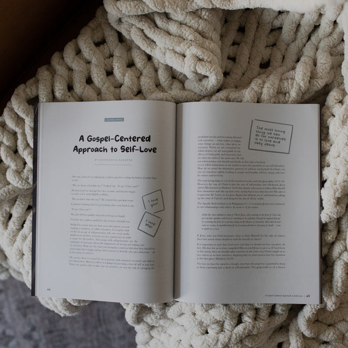 Gospel at Home Issue 7 opened to gospel centered approach to self love page on a white knitted blanket