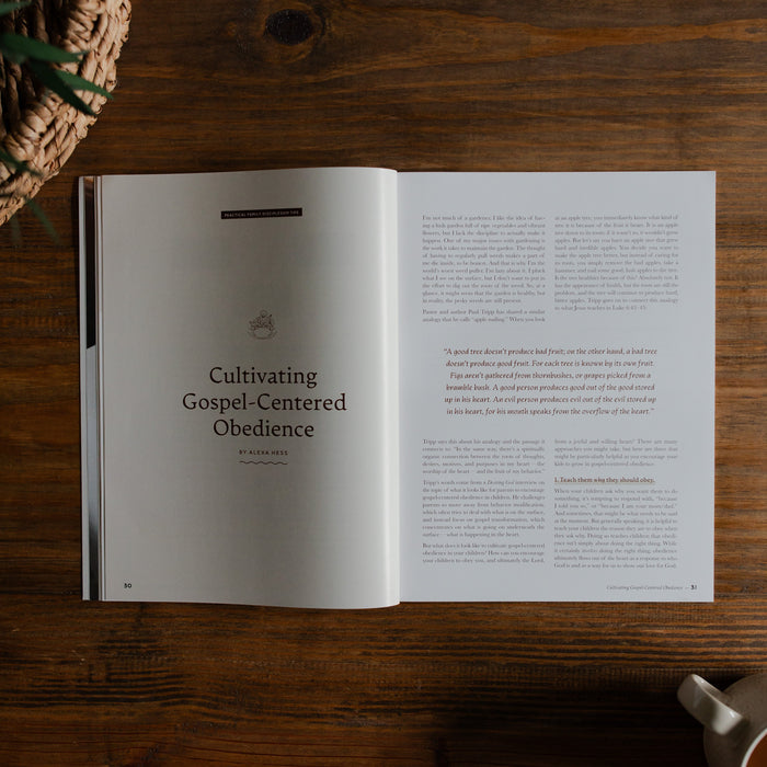 Gospel at Home Issue 8 opened to the cultivating gospel-centered obedience Page on a wooden table next to a coffee cup and a woven basket