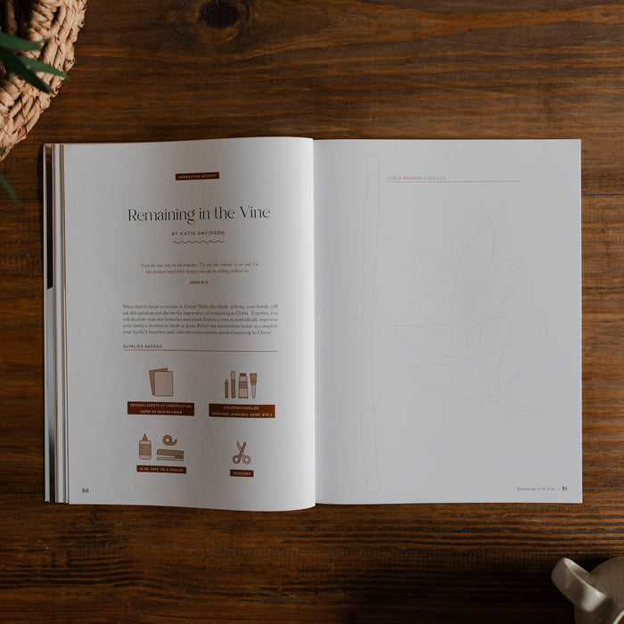 Gospel at Home Issue 8 opened to the remaining in the vine Page on a wooden table next to a coffee cup and a woven basket