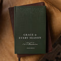 Green book titled 'Grace in Every Season' on a brown leather surface