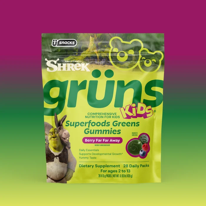 Yellow-green Shrek Kids Grüns Superfoods Greens Gummies package featuring Shrek and Donkey, labeled Berry Far Far Away flavor, listing Daily Essentials, Supports Developmental Growth, Yummy Taste, Dietary Supplement, 28 Daily Packs, for ages 2 to 13, on a purple-to-green gradient background.