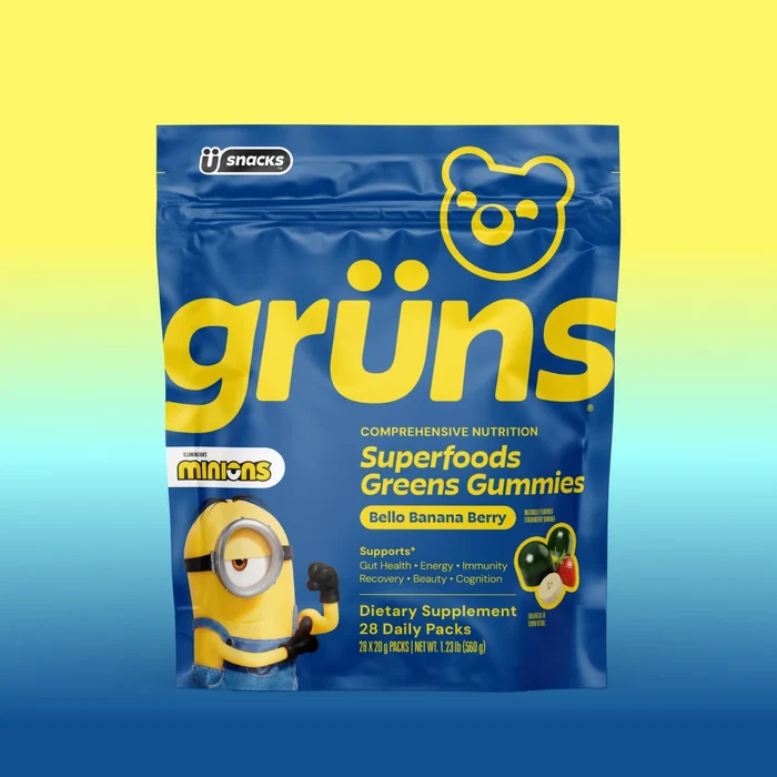 Blue Grüns Superfoods Greens Gummies bag in Bello Banana Berry flavor with Minions branding, on a yellow-to-blue gradient background