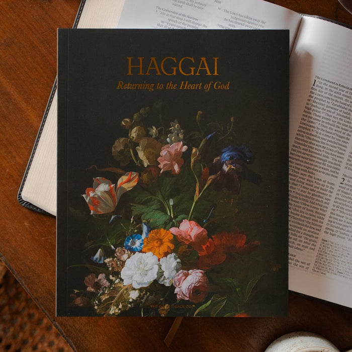 Haggai study cover on an open bible on a wooden desk near a coffee cup and a pair of eyeglasses