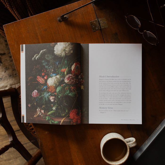 Haggai study opened to the week 1 introduction page on a wooden desk near a pair of eyeglasses
