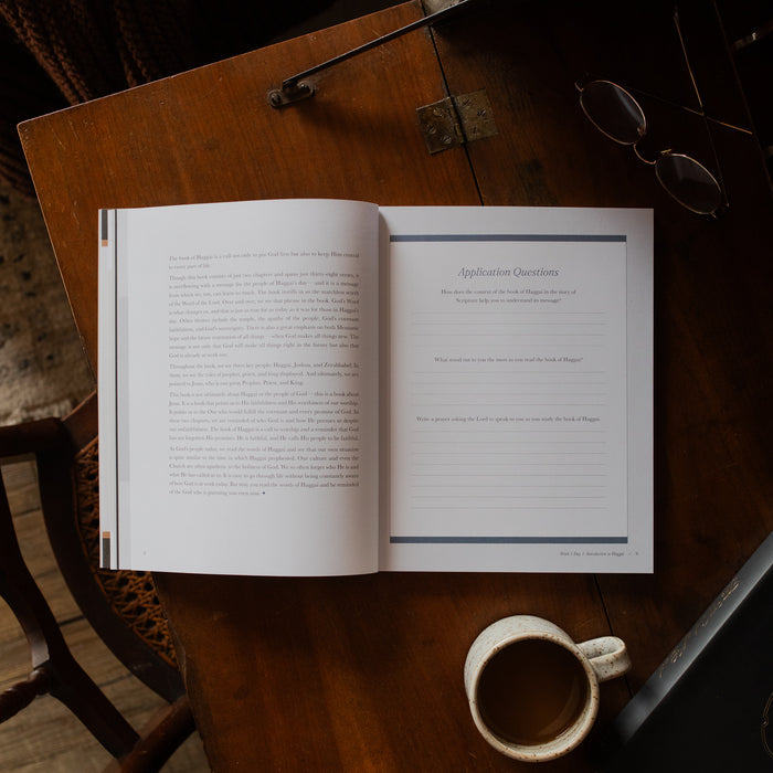 Haggai study opened to the applications page on a wooden desk near a pair of eyeglasses