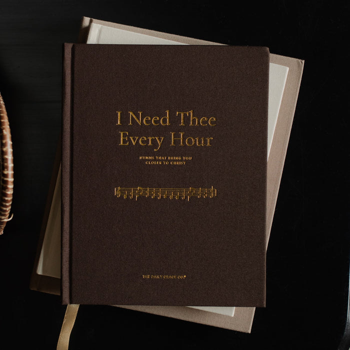 The I Need Thee Every Hour on a closed book on a black table