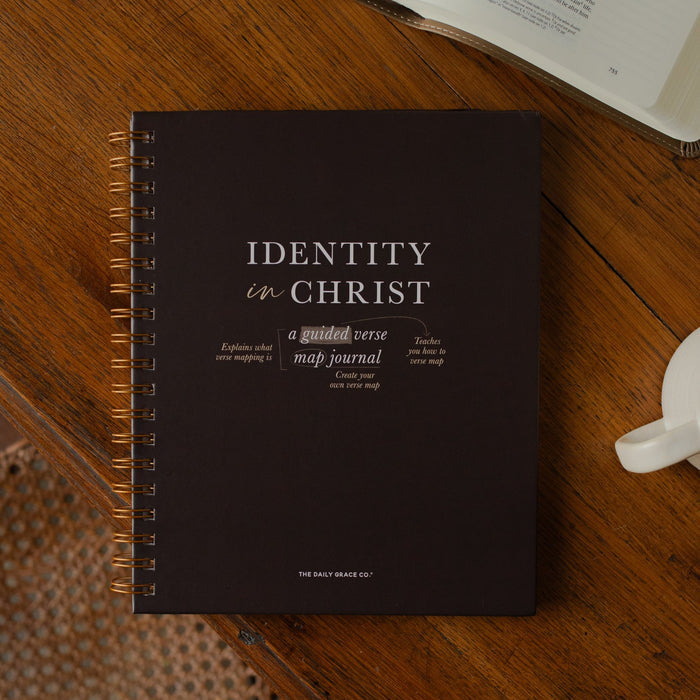 Identity in Christ Verse Map Journal on a wooden table near a coffee mug and an open bible