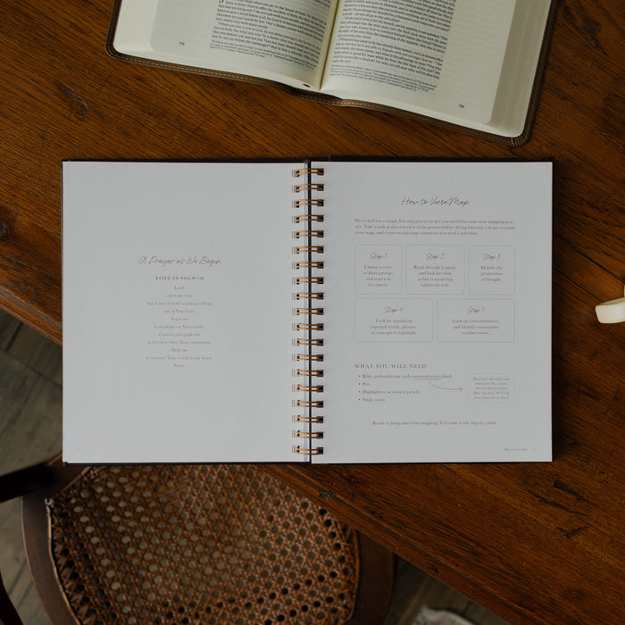 Identity in Christ Verse Map Journal opened to the how to verse map page on a wooden table near a coffee mug and an open bible