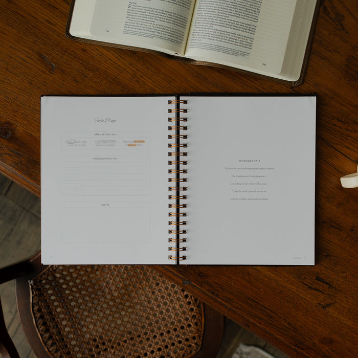 Identity in Christ Verse Map Journal opened to a Verse Map page on a wooden table near a coffee mug and an open bible