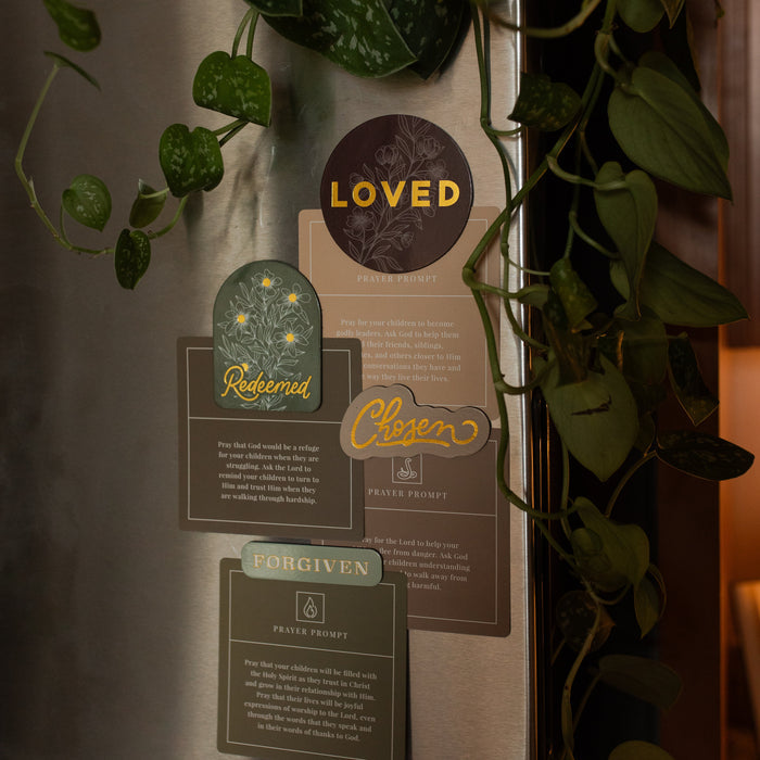 All of the Identity Magnets holding verse cards to a refrigerator near greenery