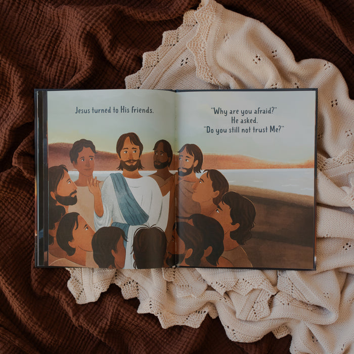 Jesus Calms the Storm Picture Book opened to Jesus talking to his friends page on a white and brown blanket