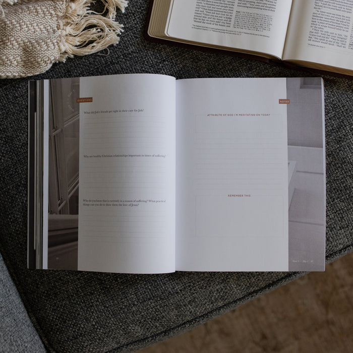 The Job Study Men's version opened to the questions and notes page next to an open bible on a gray couch