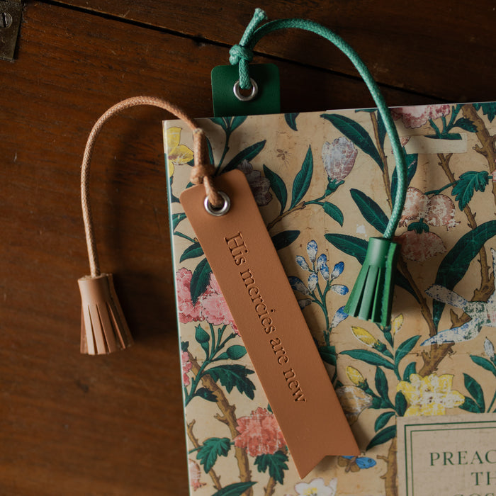 The Leatherette Bookmarks on an open book and one in a book on a wooden table