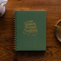 The Gospel Changes Everything Not taking Journal on a wooden table next to a coffee cup and an bronze oil lamp