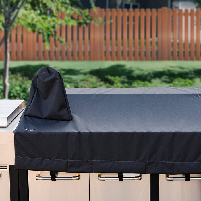 Dark blue outdoor grill cover with brand logo, protecting grill on patio.