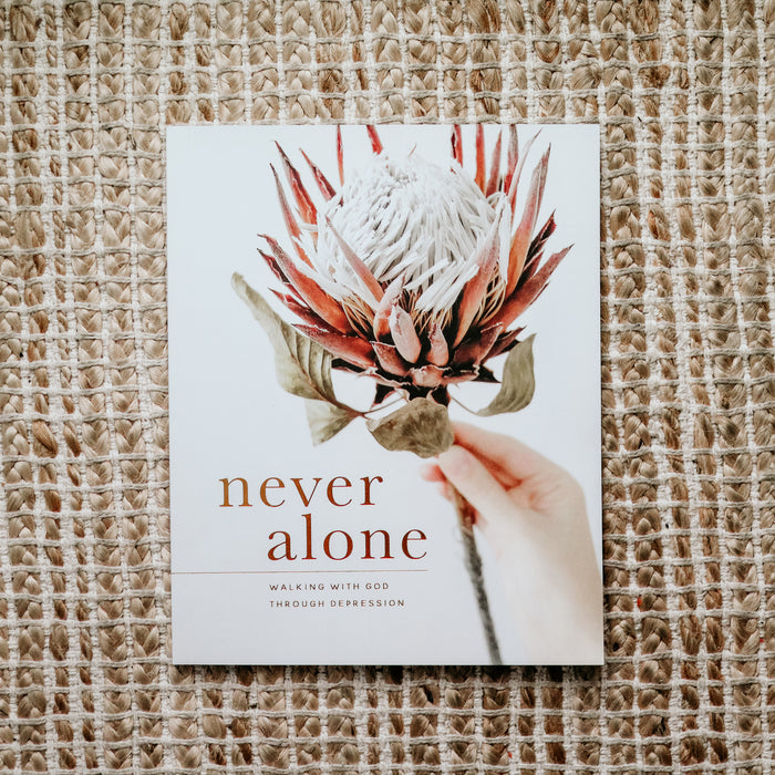 Image of the cover of the Never Alone Bible study. The cover is of a person holding a bloomed artichoke. The colors are white, red, and green.