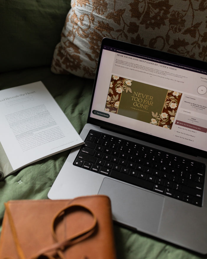 Group leader guide displayed on a laptop with the Bible study open with a closed Bible on a green couch