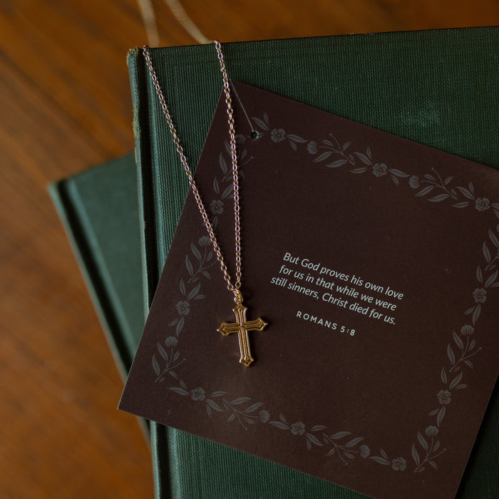 Ornate cross necklace on multiple green journals