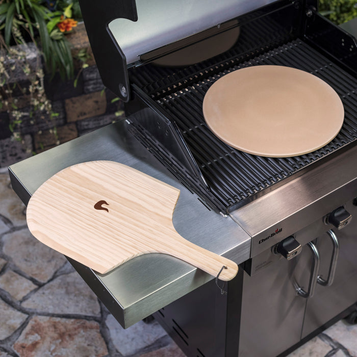 Silver Char-Broil grill with wooden pizza peel and round pizza stone.