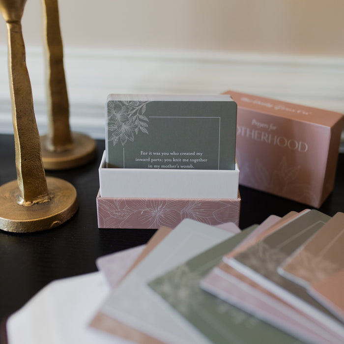 Prayers for Motherhood verse cards in a pink flowery case opened to reveal multiple cards on a dark table with multiple verse cards on the table