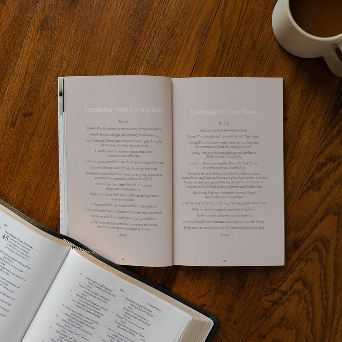 The Prayers for your Day opened to the engaging with co-workers page on a wooden table near a coffee cup