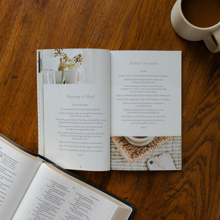 The Prayers for your Day opened to the sharing a meal page on a wooden table near a coffee cup