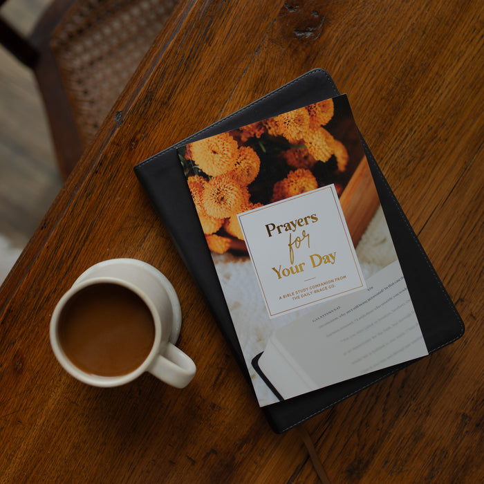 The Prayers for your Day on a bible on a wooden table near a coffee cup