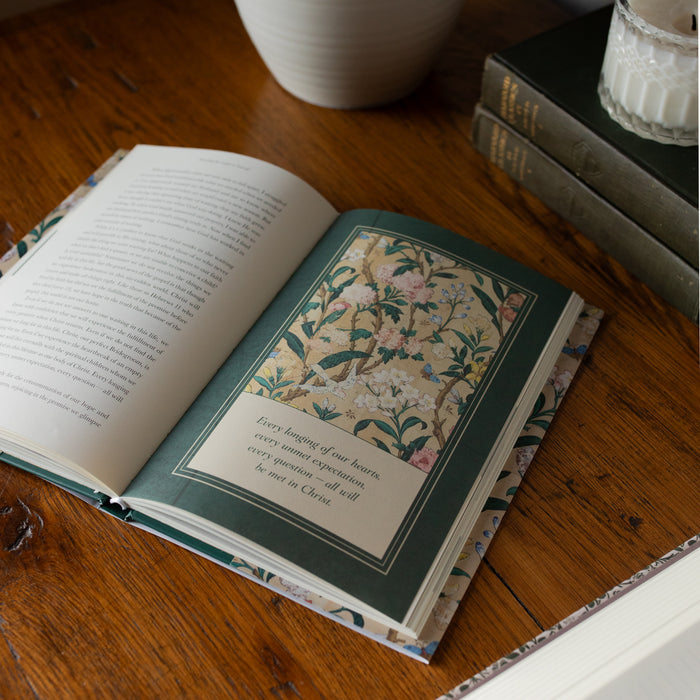 Preaching the Gospel to yourself angled to a corner opened to the Every longing of our hearts page on a wooden table