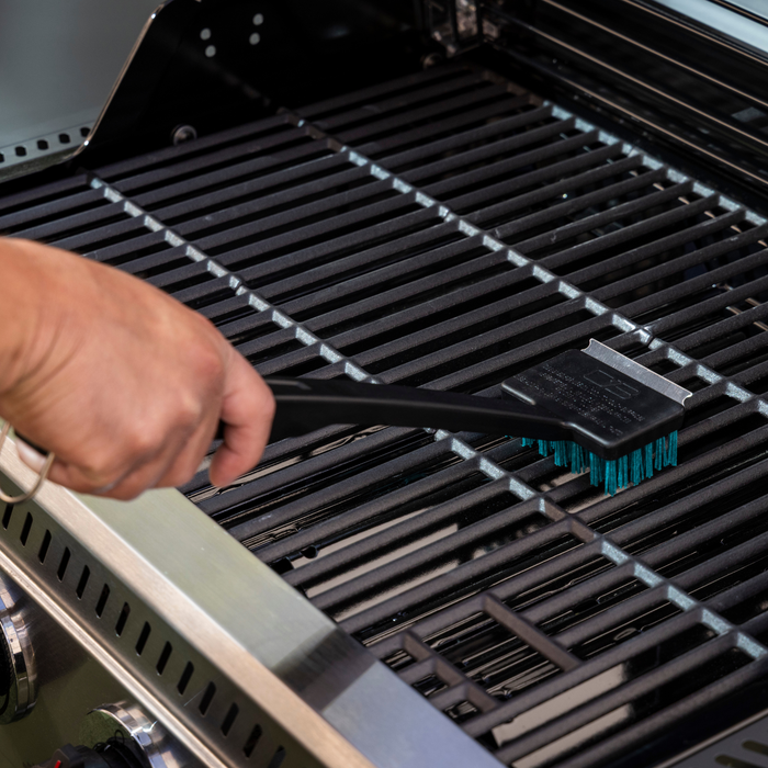 Black grill grate with built-in thermometer and cleaning tool.