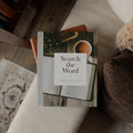 Book titled 'Search the Word' on a couch with a cup of coffee and plant in the background