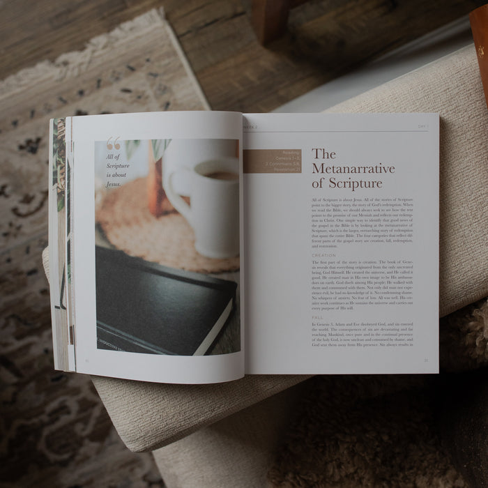 Open book on a textured surface with a cup of coffee and bread in the background