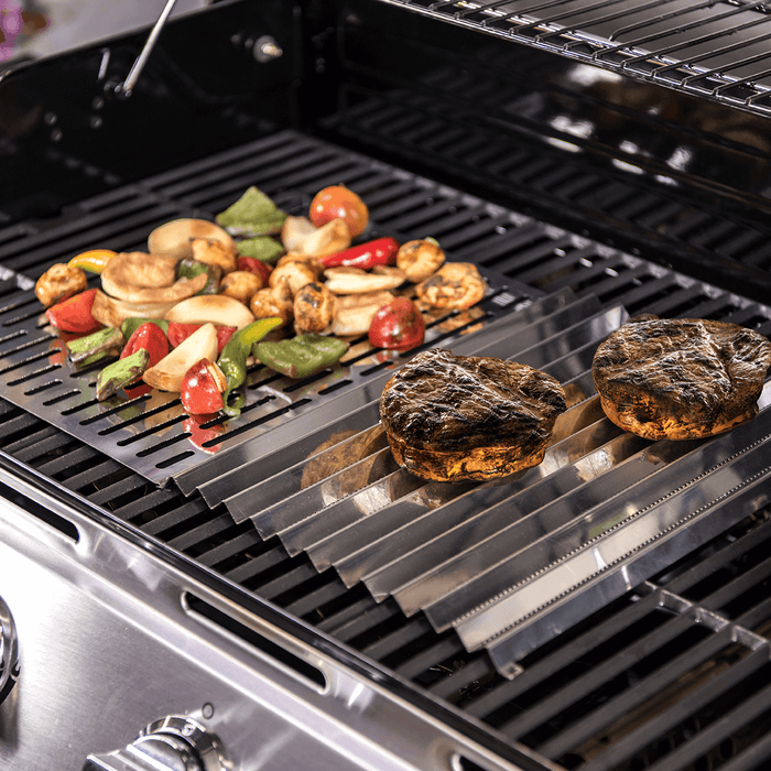 Black grill with steaks and vegetables cooking.