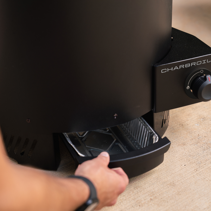 Black Char-Broil electric grill with control knob and hand adjusting.