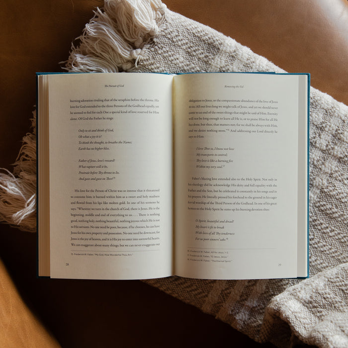 The Pursuit of God opened to page 28 on a cream blanket and leather couch