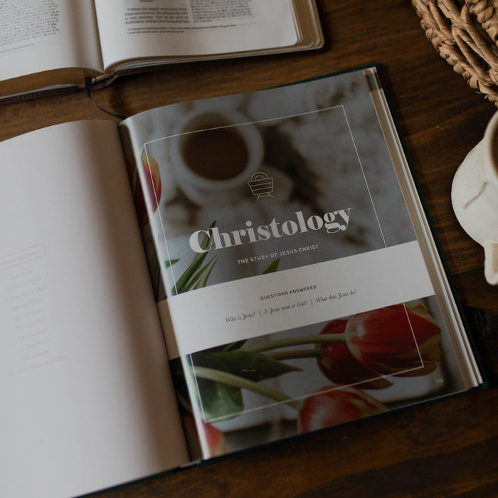 Book titled 'Christology' on a wooden surface with another book open in the background.