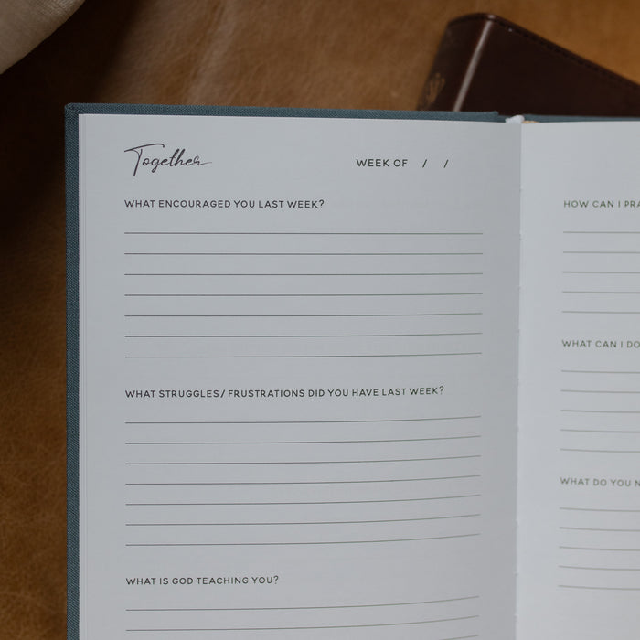 Open notebook with reflective questions on a wooden surface