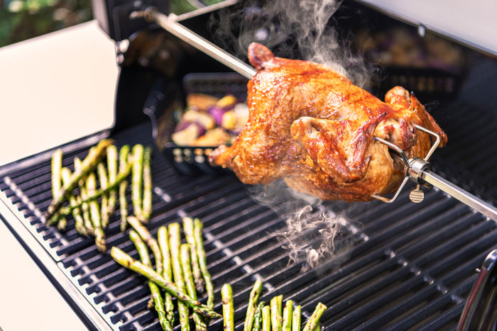 Grilled chicken on a barbecue with asparagus and vegetables.