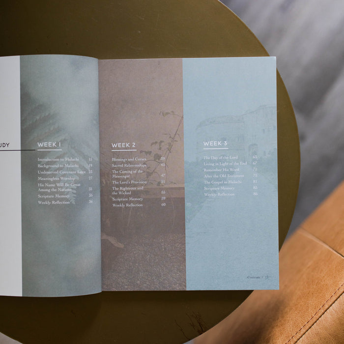 Mens Malachi Waiting for Hope Bible Study opened to a table of contents page for weeks 2 and 3 sitting on a gold colored table