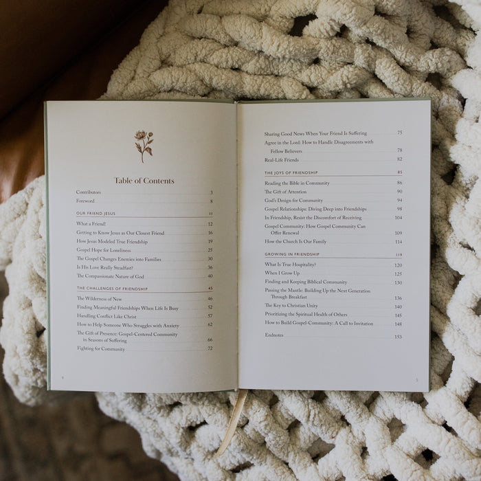 What a friend we have in Jesus opened to the Table of Contents page on a white knitted blanket on a leather couch